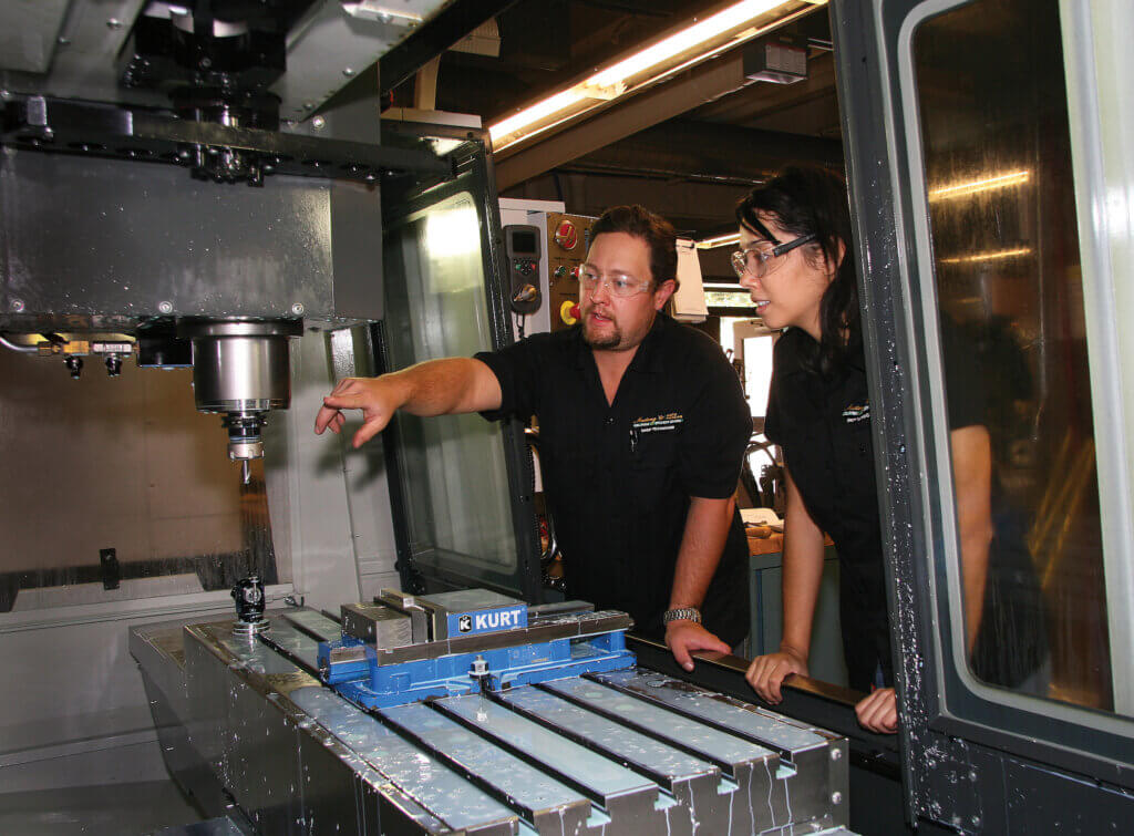 Mustang ’60 Shop: Eric Pulse and Allian Roman work on new Haas VF3 milling machine.